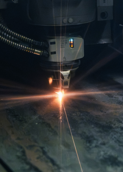 Eine Lasermaschine schneidet eine Metallplatte. Ein heller Lichtstrahl erzeugt Funken auf der Oberfläche.